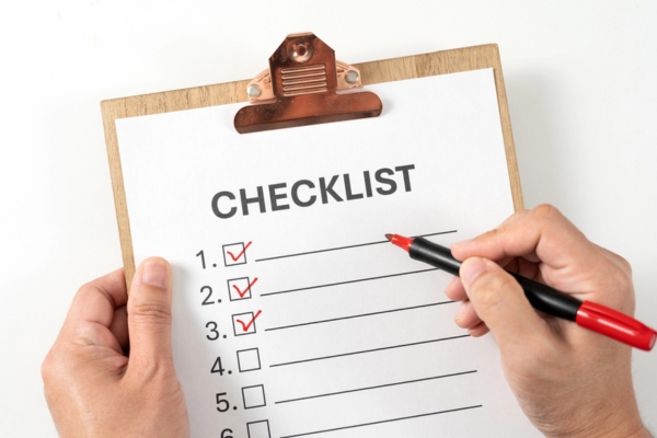 Checklist on the wooden clipboard, hands using a red marker depicting post cooling system installation
