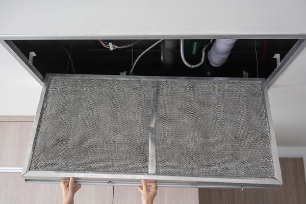 image of a dirty furnace filter and homeowner replacing it
