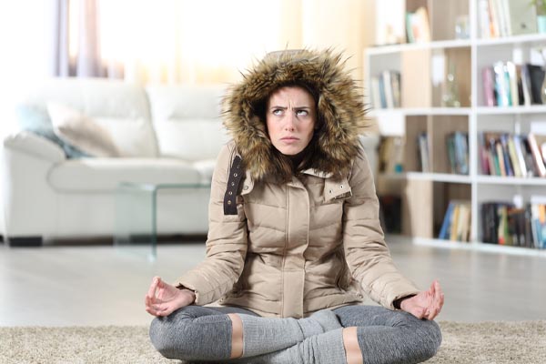 image of a homeowner feeling chilly due to furnace turning on but no heat