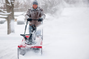 man snowblowing to clear a path for an oil delivery