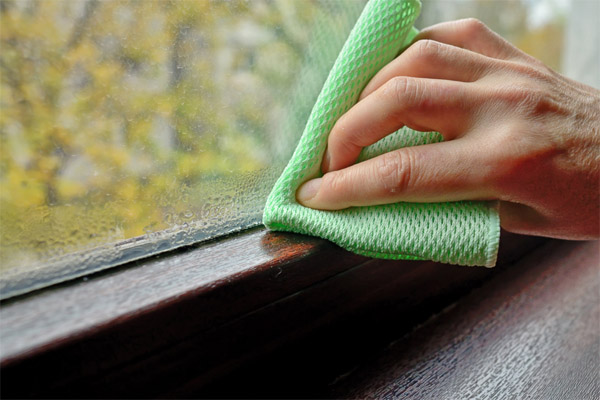 woman cleaning indoor condensation from window