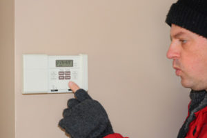 image of a man adjusting thermostat due to broken furnace