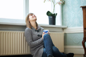 homeowner relaxing next to boiler radiator