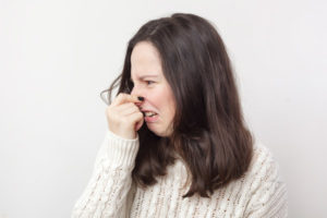 image of a homeowner plugging nose due to dead animal in ductwork