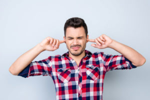 image of a man covering ears because air conditioner noises