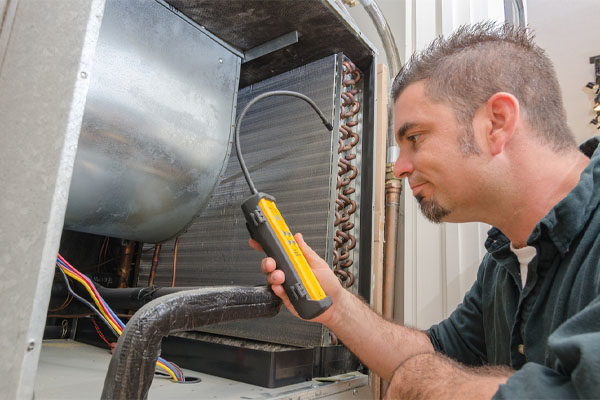 hvac technician with refrigerant air conditioner leak detector