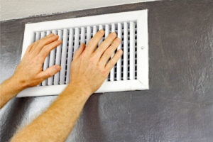 image of hands in front of air conditioner vent due to ac blowing warm air