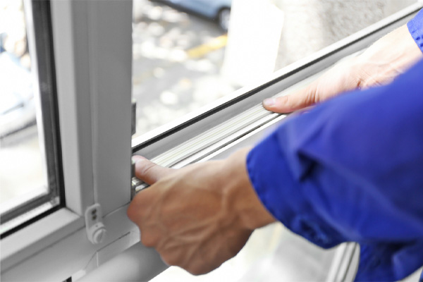 image of homeowner placing foam tape on window to prevent air drafts