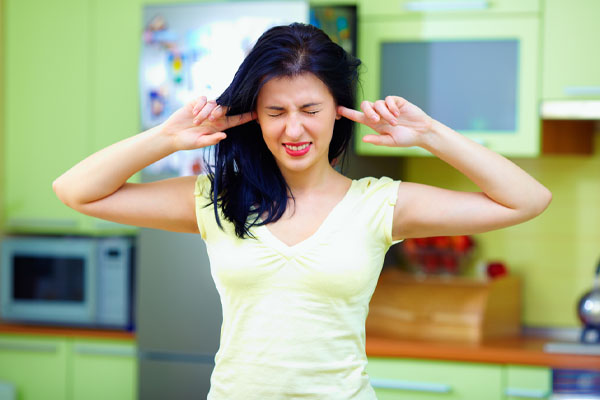 image of a homeowner who is plugging ears due to ac making noise