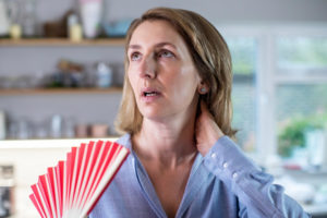 image of a homeowner using a fan to keep cool due to heat pump blowing hot air in cool mode