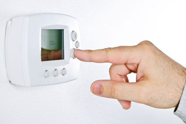 image of homeowner adjusting programmable thermostat