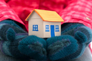 image of hands with mittens holding house depicting home heating and furnace and heat pump