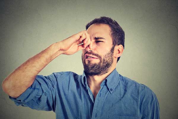 image of a homeowner plugging nose due to furnace odor and overheating