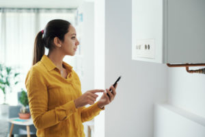 homeowner controlling smart boiler with phone depicting smart home heating