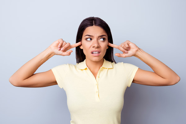 image of homeowner covering ears due to air conditioner noises