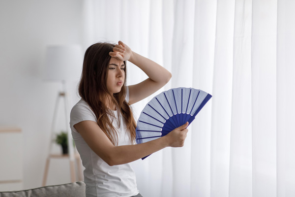 image of a homeowner feeling hot due to air conditioner that is blowing warm air