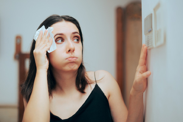 image of a homeowner looking at thermostat due to air conditoner not cooling