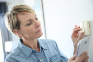 image of a homeowner adjusting thermostat depicting furnace that wont turn off