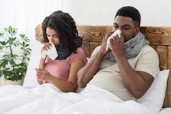 image of a sick couple in bed depicting poor iaq