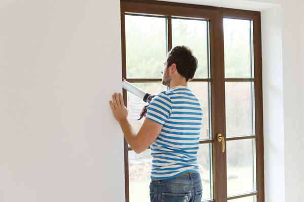 image of a man with caulking gun and sealing air drafts