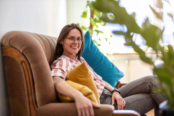 woman sitting on a couch depicting Advantages of Installing a High-Efficiency AC System