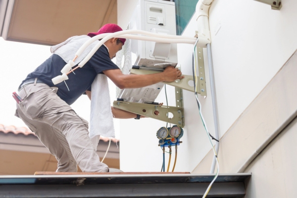 male HVAC technician installing an outdoor air conditioner unit