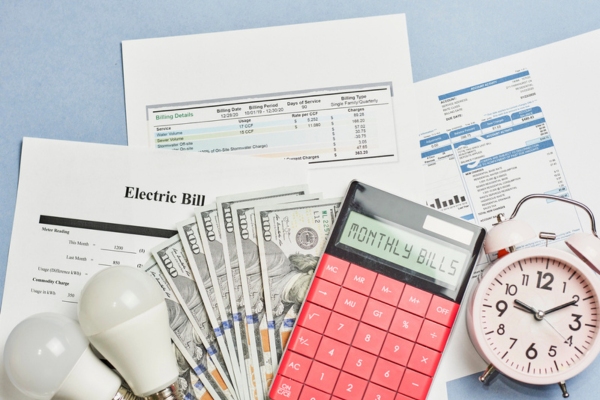 Monthly utility bills with currency bills, calculator, and alarm clock