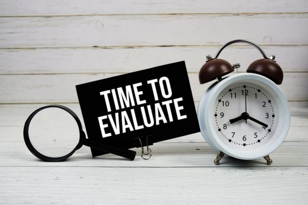 time to evaluate written on a card beside an alarm clock depicting air conditioner repair vs replace