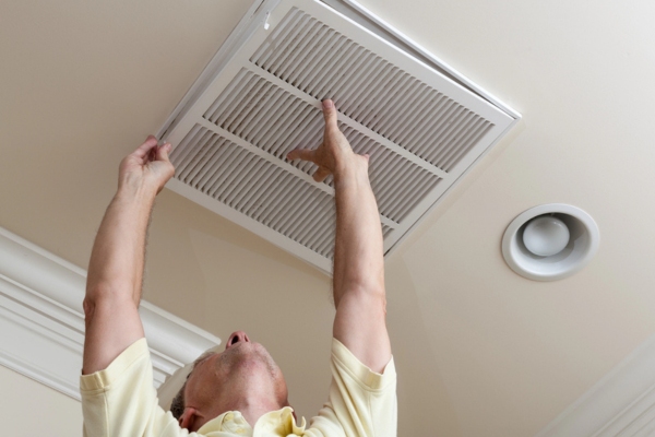 homeowner checking home HVAC filter in the ceiling