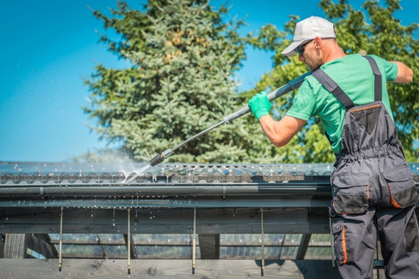 man cleaning Roof and Gutters Using Pressure Washer