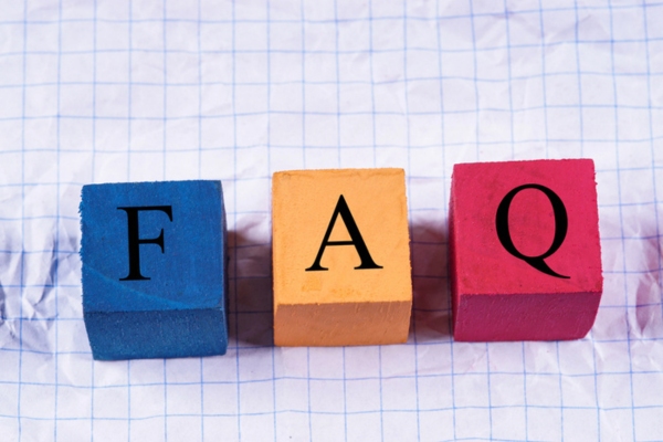 FAQ spelled using wooden letter cubes on top of a crumpled paper depicting questions about oil prices