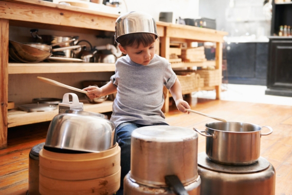 little kid banging pots in the kitchen depicting banging sounds from furnace