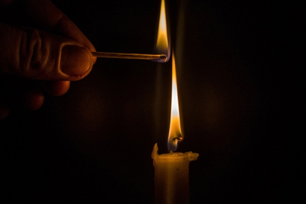homeowner lighting a candle with a matchstick during power outage