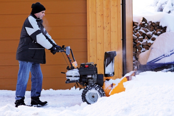 man clearing snow beside the house