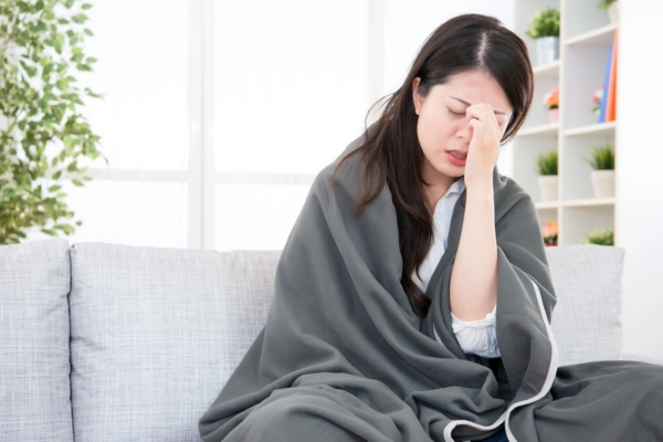 sick woman experiencing headache and nausea while on the couch depicting carbon monoxide poisoning