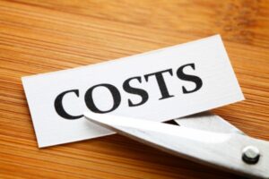 cutting the word COSTS printed on a small paper depicting Cutting Costs With Efficient Heating Oil Delivery Service