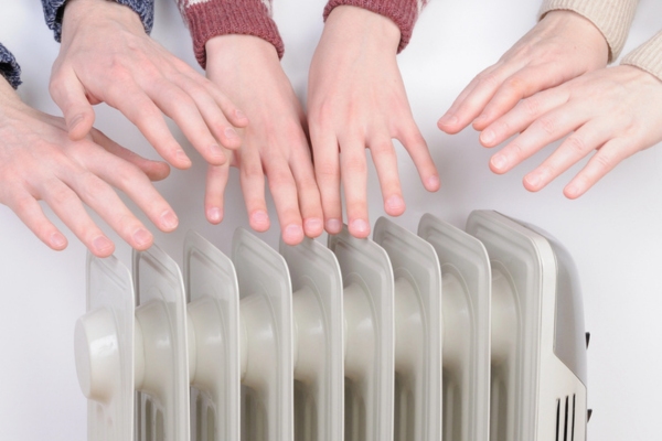 family warming up hands using an electric space heater