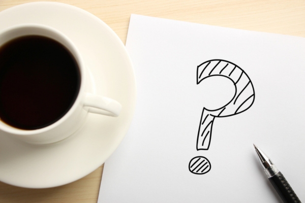 question mark doodled on paper beside a coffee cup depicting Heating Oil Delivery Services FAQs