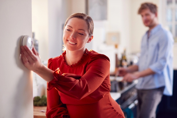 woman adjusting home thermostat
