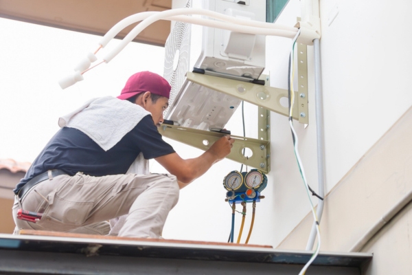 Technician man tending to the outdoor unit of a ductless air conditioner