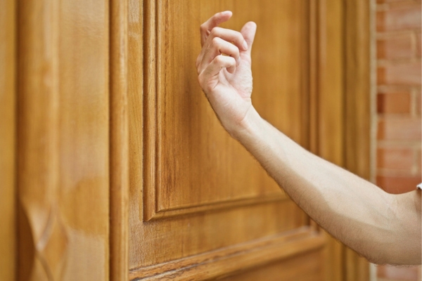 man's hand about to knock on a door