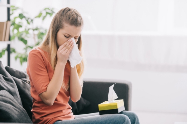 woman on the couch feeling sick due to Dust Buildup Indoors