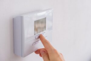 homeowner's hand adjusting home thermostat