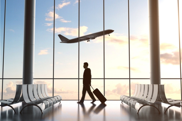man's silhouette standing by the glass window with a plane in the background depicting How Air Conditioning Improves Public Spaces