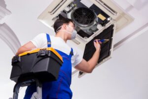 HVAC technician tending to ceiling air conditioner