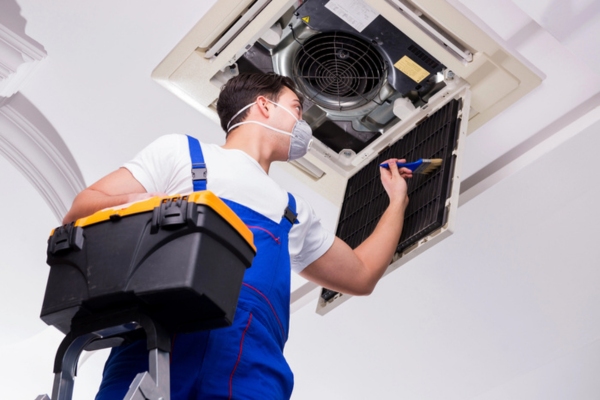 HVAC technician tending to ceiling air conditioner