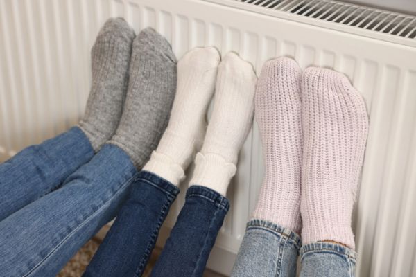 Family warming feet near heating radiator at home