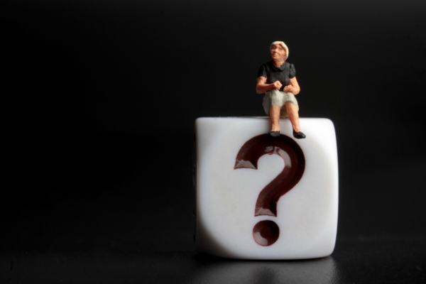 question mark on a plastic dice with miniature figure of a woman on top depicting Questions About HVAC Installation Cost