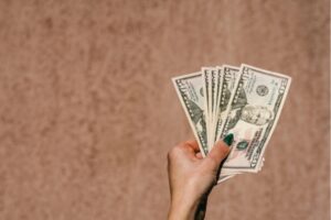 woman's hand holding dollar bills depicting Factors Affecting HVAC Installation Costs