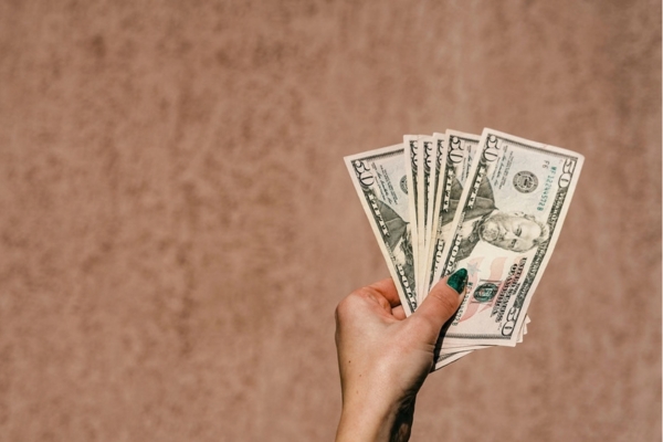 woman's hand holding dollar bills depicting Factors Affecting HVAC Installation Costs